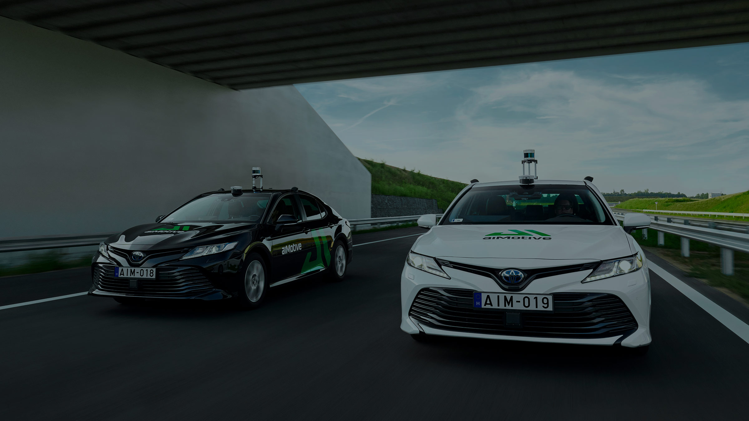 Two automated driving cars developed by aiMotive under a highway pass